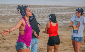People dancing on a beach with headphone on
